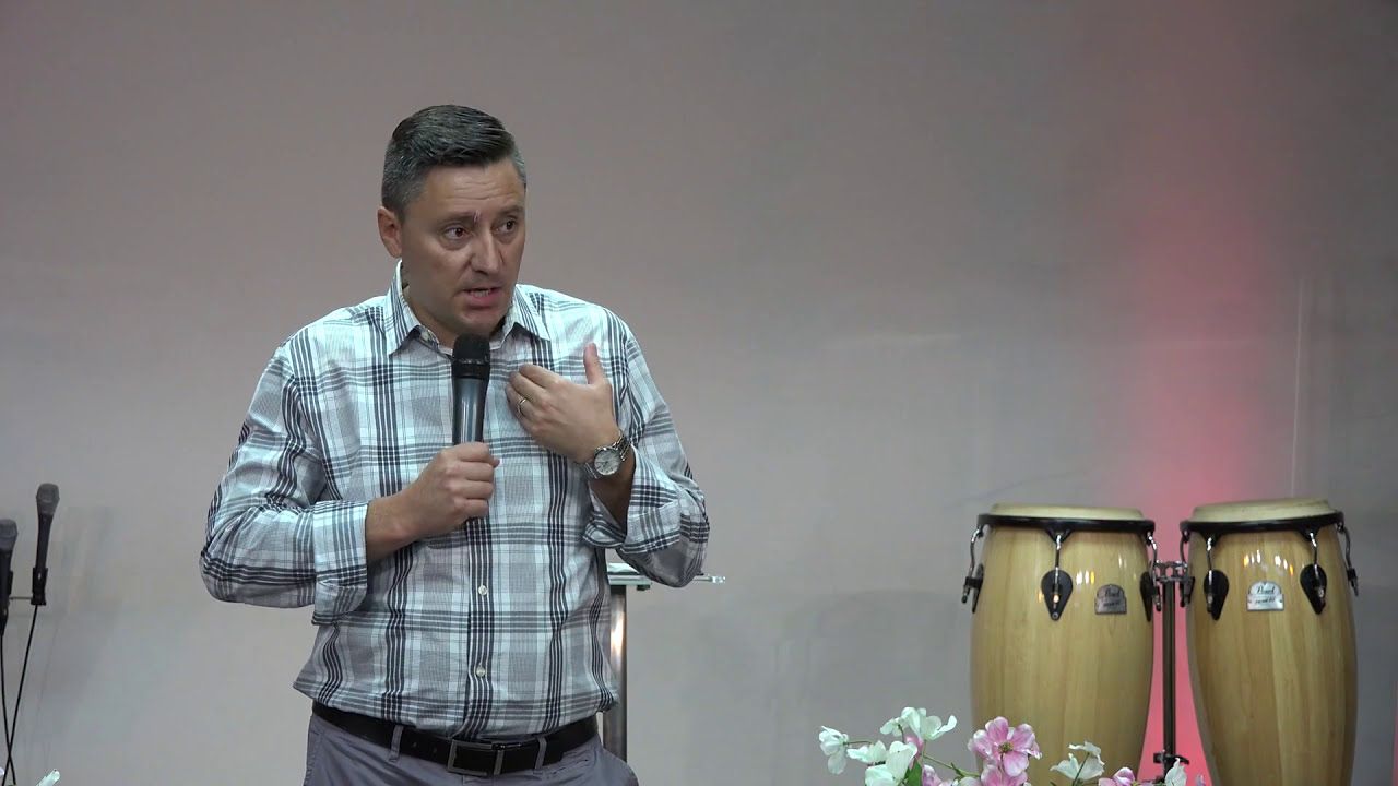 Ruslan Murin preaching into a microphone with one hand on his chest.