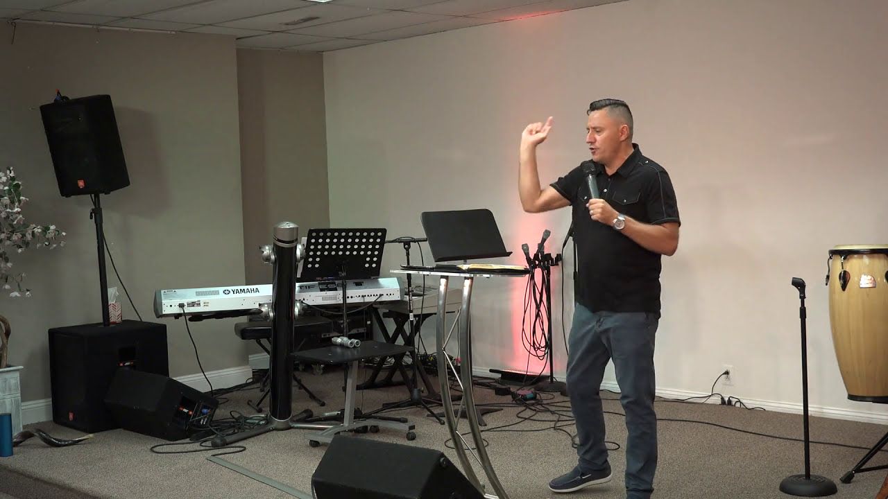 Ruslan Murin in a black shirt preaching into a microphone with one hand raised.