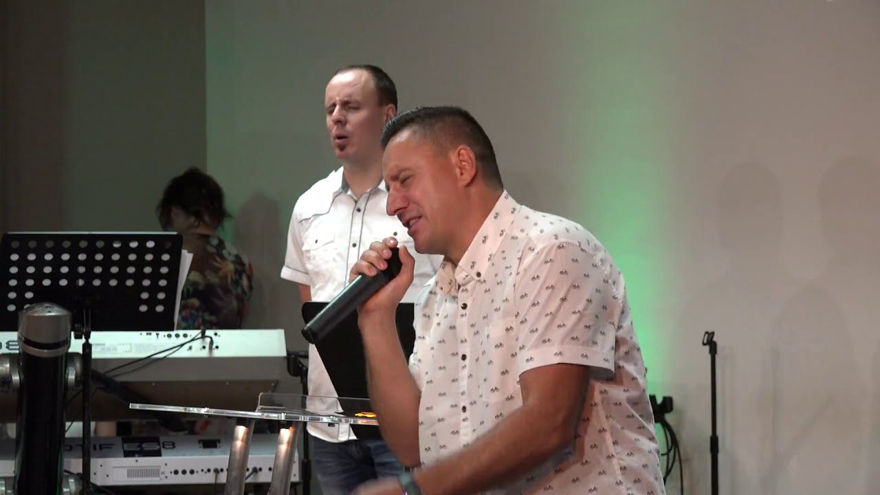 Ruslan Murin speaking into a microphone with his eyes half closed, another man standing behind him.